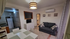 A compact living space with a dining area, kitchenette, and a sofa.