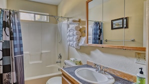 Un baño con ducha, inodoro, lavabo y espejo.