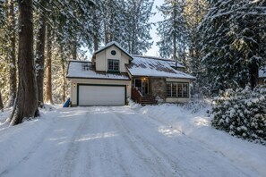 Ett tvåvåningshus med ett snötäckt tak, ett garage och en uppfart som leder fram till entrén.