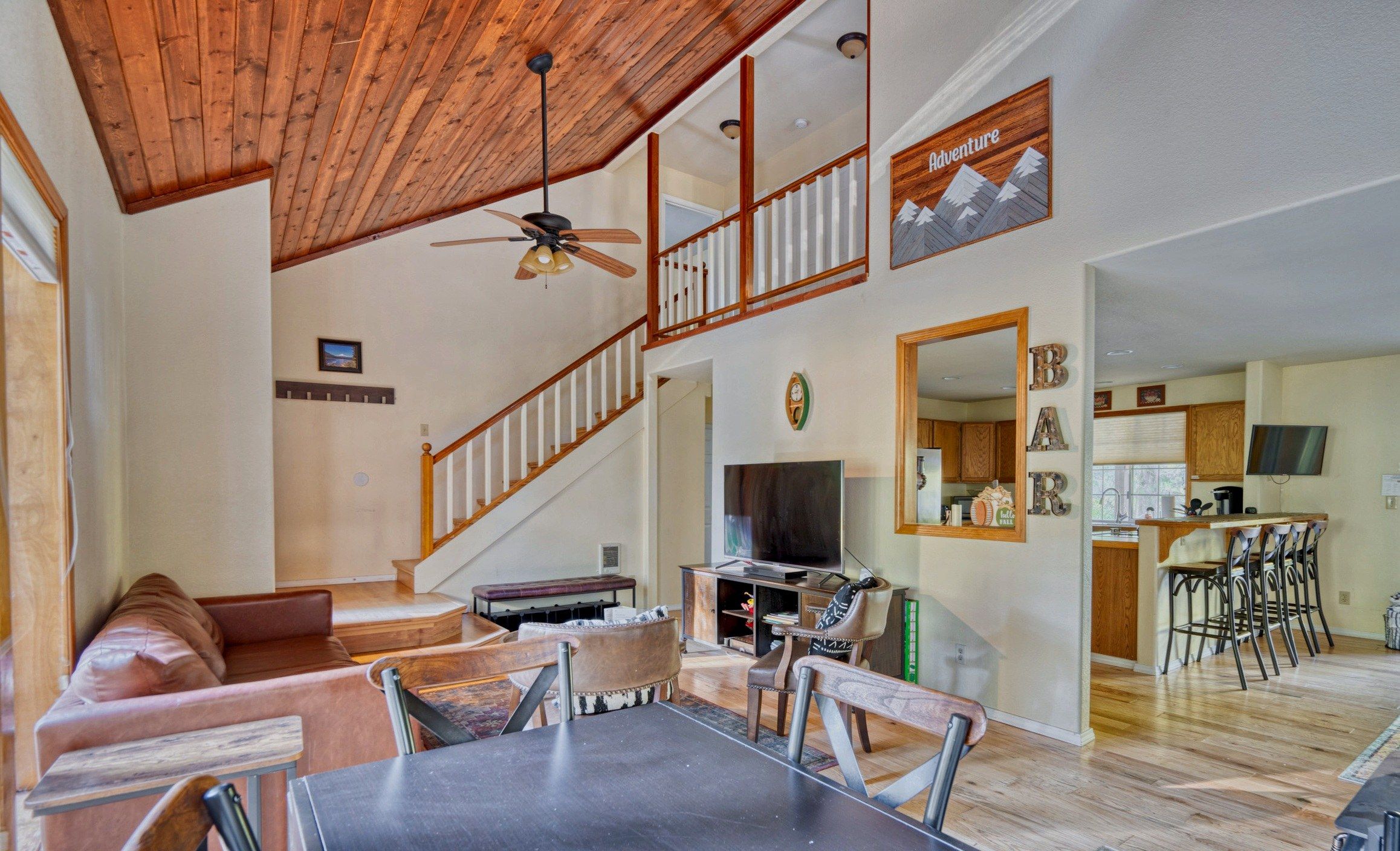 A spacious living area with a high ceiling, a dining table, and a kitchen area with a bar.