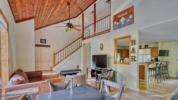 A spacious living area with a high ceiling, a dining table, and a kitchen area with a bar.