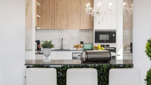 Une cuisine moderne avec des meubles en bois, un micro-ondes Bosch noir, une machine à café et un grille-pain vert.