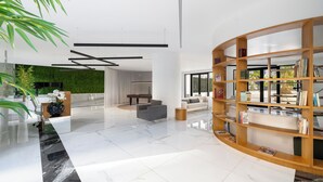 Un hall d’entrée moderne avec un sol en marbre, une bibliothèque en bois et un mur végétal.
