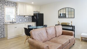 Une cuisine moderne avec des meubles blancs, un réfrigérateur noir et un coin repas comprenant une table et des chaises.