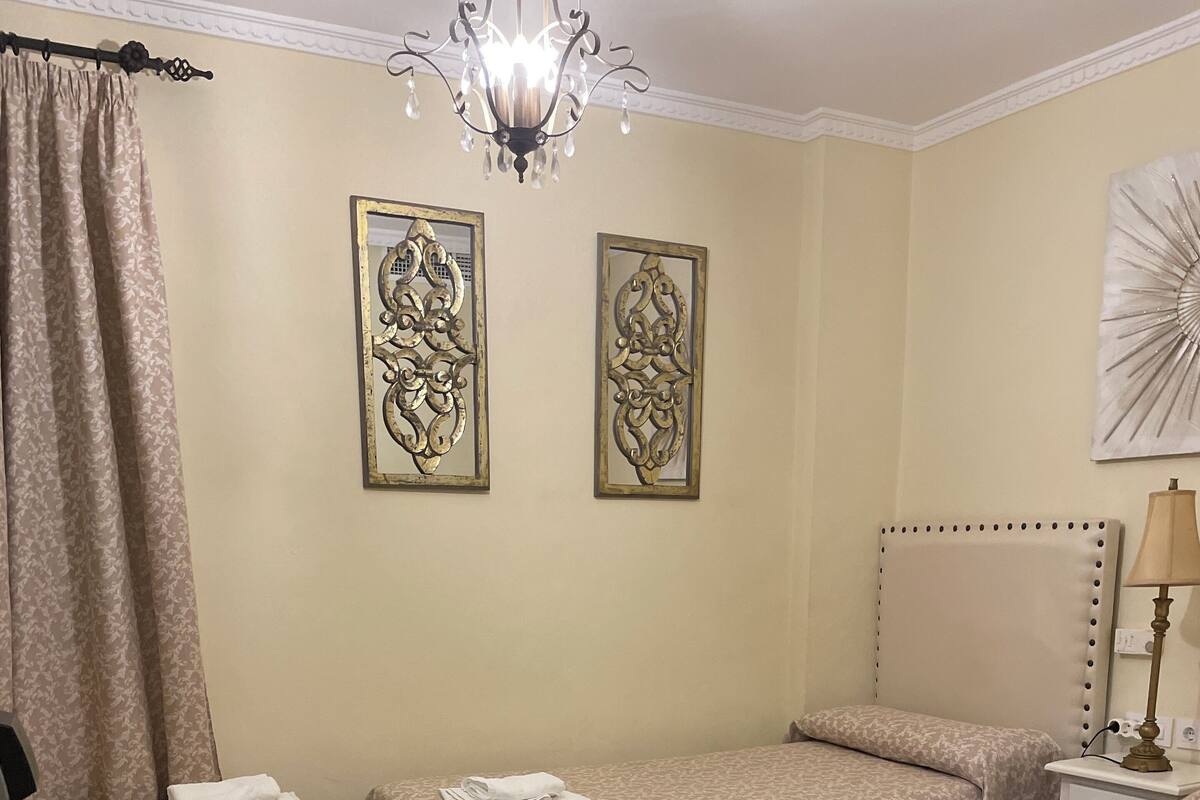 Una habitación de hotel con dos camas individuales, suelo estampado y espejos decorativos en la pared.