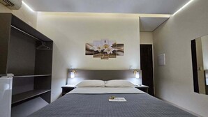 Une chambre d’hôtel comprenant un lit, des tables de chevet, une armoire et une œuvre d’art accrochée au mur.