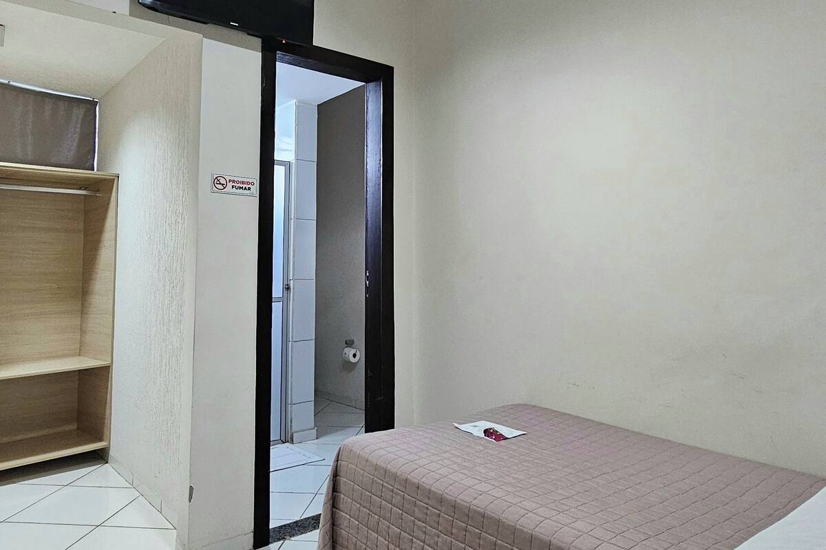 A bedroom with a bed, a wardrobe, a television, and a ceiling light.