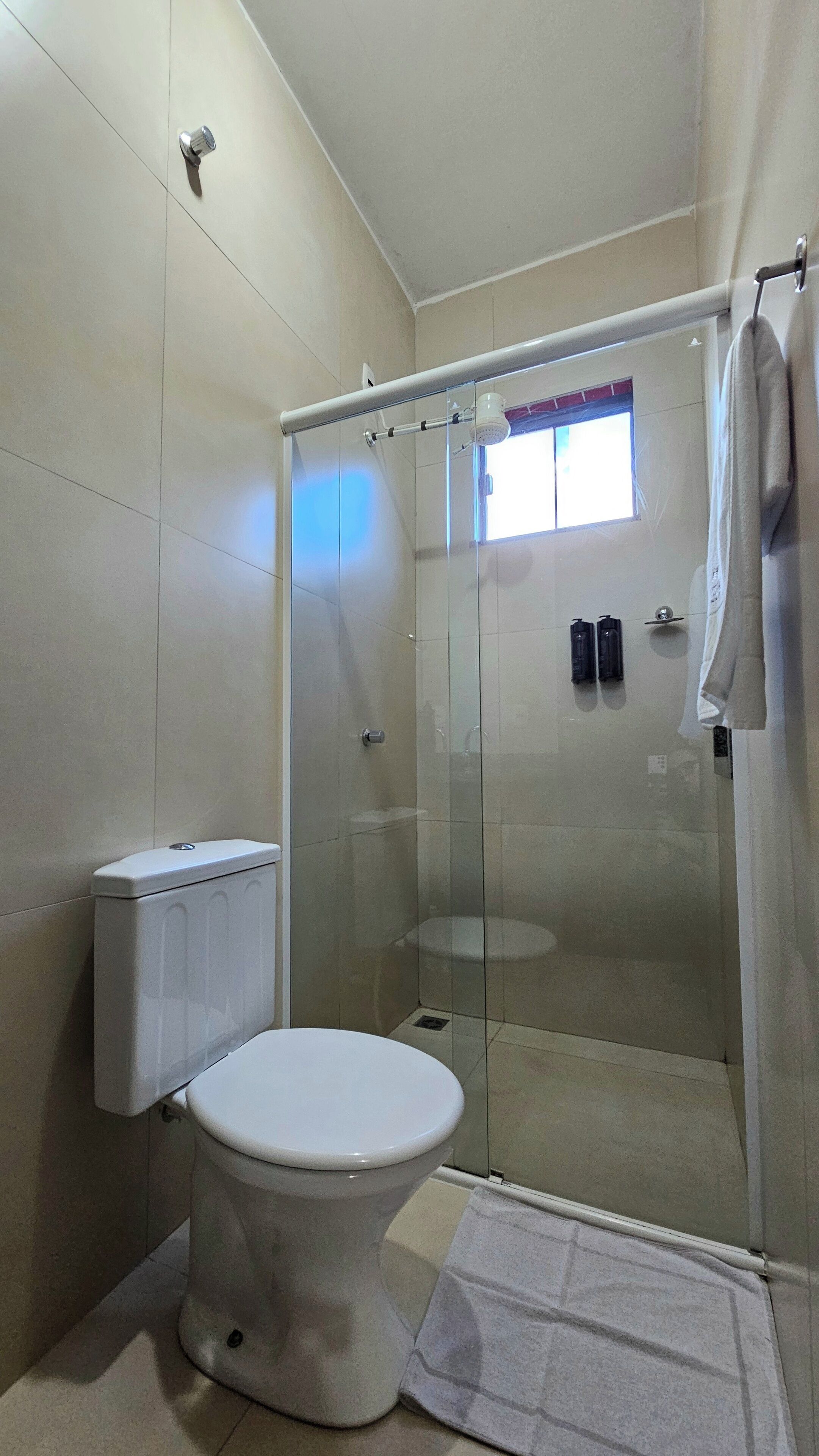 Un baño moderno con inodoro, cabina de ducha de vidrio y barra para toallas.
