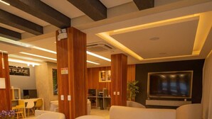 Un salon moderne avec un grand canapé d’angle, deux fauteuils, un téléviseur à écran plat et un mur décoratif en bois.