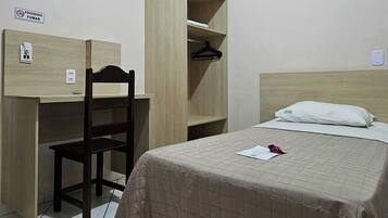 Un dormitorio con cama, escritorio de madera y armario.