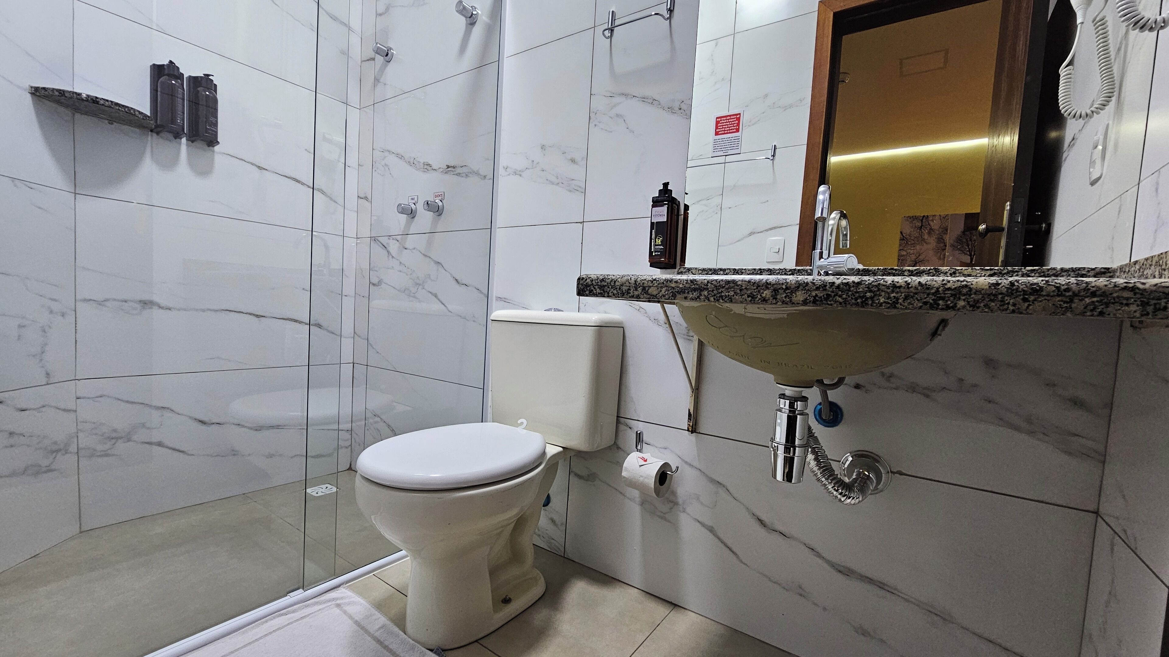 Een badkamer met toilet, wastafel en marmeren wanden.