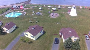 Vista aérea de una comunidad costera con casas, un faro y un parque infantil.