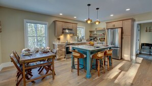 Una cocina moderna con una isla central, sillas de madera y una mesa de comedor preparada para cuatro personas.