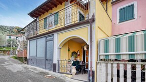 Ein zweistöckiges Gebäude mit Balkon, Schaufenster und einer kleinen Außenbestuhlung.