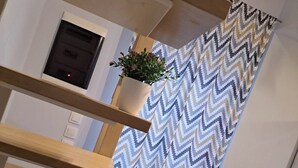 Eine Treppe mit einem Vorhang in Zickzack-Muster und einer Topfpflanze an der Wand.