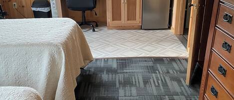 A hotel room with a bed, a desk with a computer, a microwave, and a refrigerator.