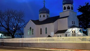 Una chiesa con due cupole e una croce sulla sommità, circondata da un recinto di legno bianco.