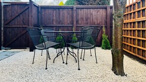 A patio with a table and chairs, surrounded by a wooden fence and a tree. - Stylish Cheshire House (Winsford)