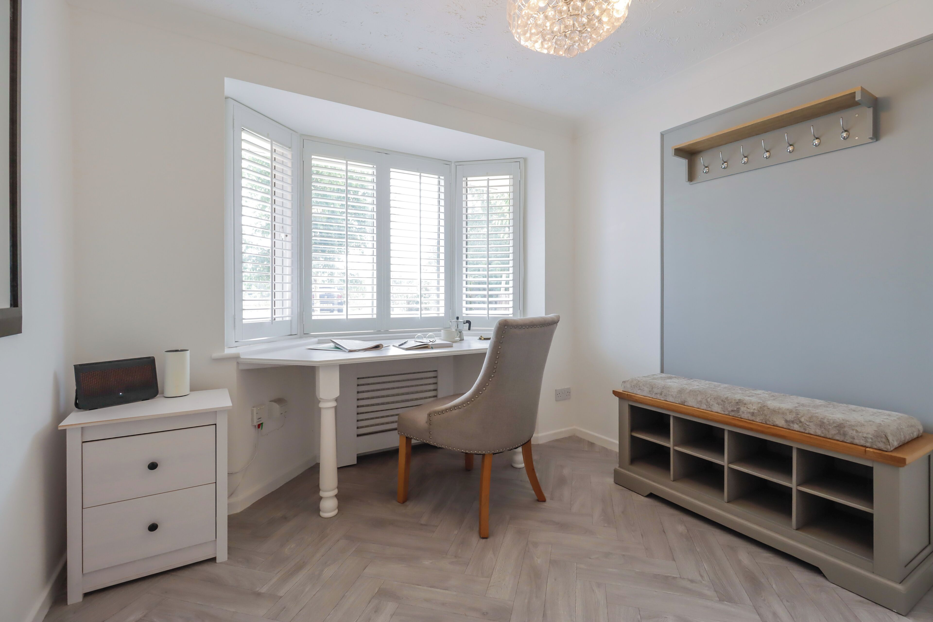 Une pièce comprenant un bureau, une chaise et un banc avec des étagères.