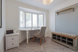 Une pièce comprenant un bureau, une chaise et un banc avec des étagères.
