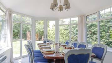 A dining room with a large table set for six, surrounded by six chairs with blue upholstery.