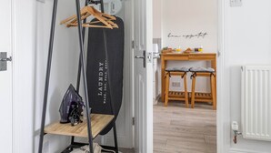 A hallway with a black laundry stand, a wooden table with chairs, and a sign on the wall. - Stylish Cheshire House (Winsford)