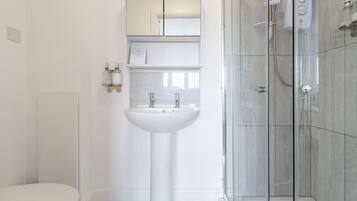 A modern bathroom with a pedestal sink, a glass shower enclosure, and a toilet.