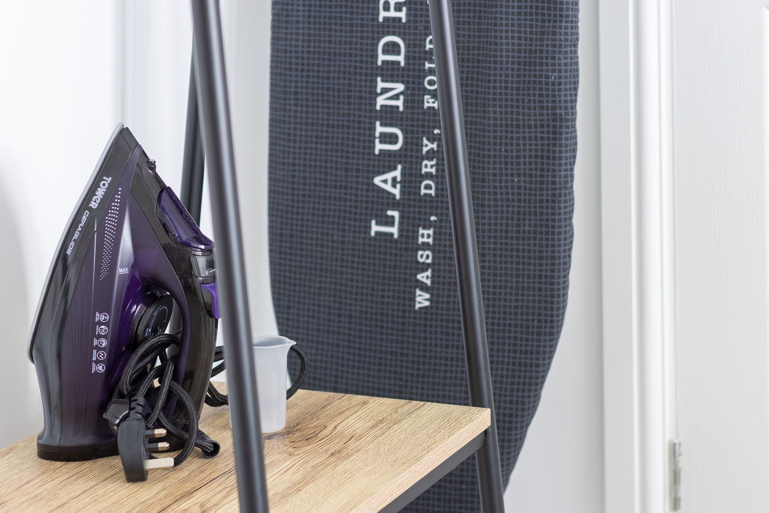A vacuum cleaner and a large laundry basket on a wooden shelf.