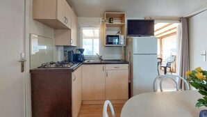 A compact kitchen with a stove, microwave, and sink. There is a dining area with a table and chairs.