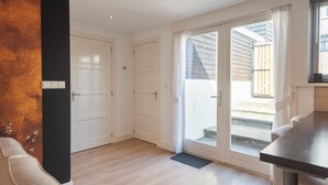 Una stanza con una porta scorrevole in vetro che dà su un balcone, un pavimento in legno e una porta bianca.