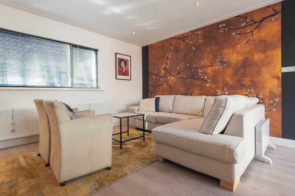 Een moderne woonkamer met een beige bank, een bijzettafeltje en een radiator.