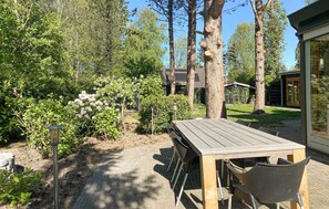 A wooden table with chairs in a garden area with trees and shrubs. - Amazing home in Lauwersoog with WiFi (Lauwersoog)