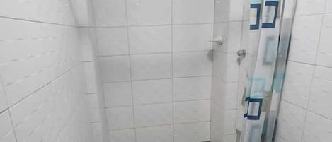 A small bathroom with a shower, a toilet, and tiled walls.