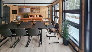 Un espace de salle à manger moderne, avec une longue table, des chaises et des luminaires suspendus.