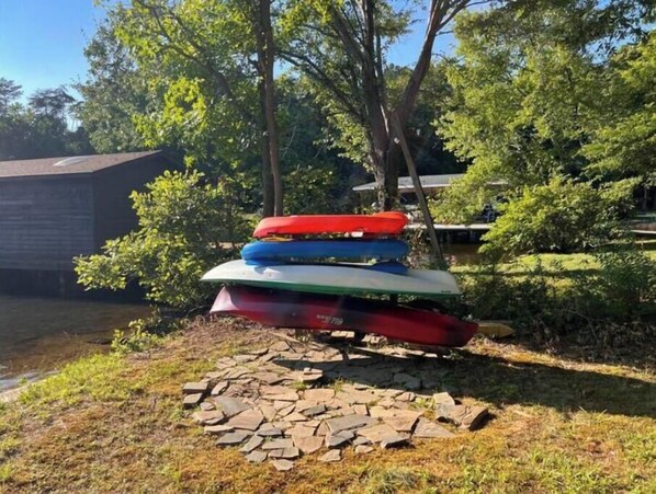 A stack of kayaks on a stone base outdoors.