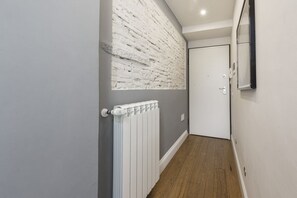 Un pasillo con pared de ladrillo blanco, un radiador blanco y una puerta.