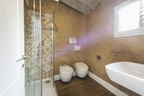 A bathroom with a shower, bidet, toilet, and bathtub.