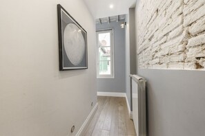 Un couloir avec un tableau encadré, un radiateur et un mur en briques.