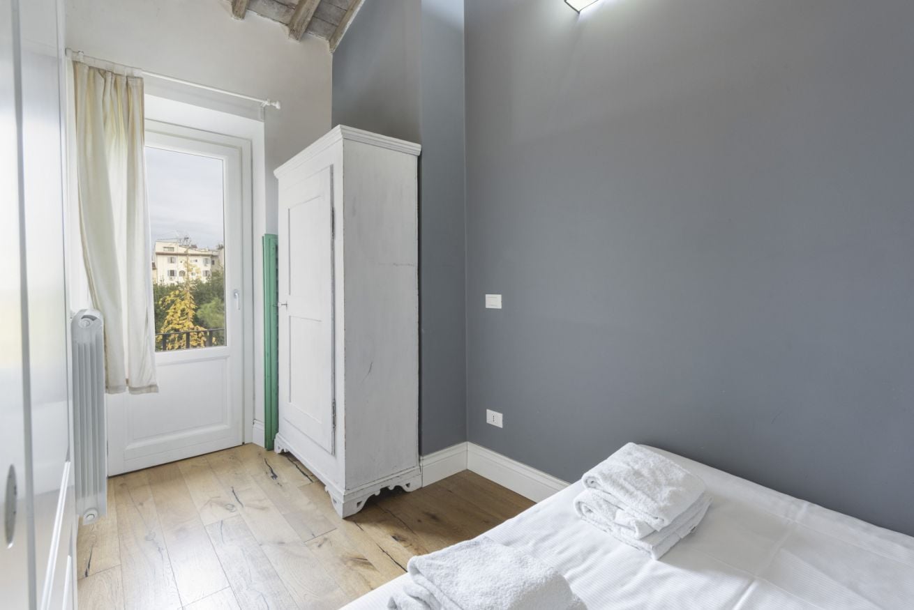 A bedroom with a bed, a wardrobe, a radiator, and a window with curtains.