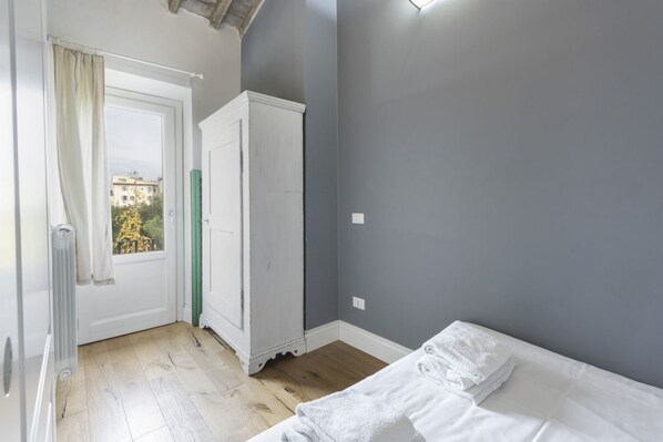 A bedroom with a bed, a wardrobe, a radiator, and a window with curtains.