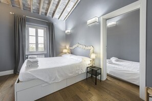 A bedroom with a bed, bedside table, lamp, and a window with curtains.