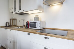 Une cuisine moderne équipée d’un évier à deux bacs, d’une machine à café, d’un four à micro-ondes et d’un meuble de rangement au-dessus du plan de travail.