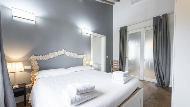 A bedroom with a large bed, bedside lamps, a chair, and a sliding glass door. - <h3>Central Nest</h3>Located in Via Guelfa, in the heart of the historic center of Florence, this delightful apartment offers a comfortable and modern refuge just steps away from the Central Market and the Santa Maria Novella Station.On the third and top (Firenze)