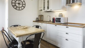 A kitchen with a wooden table, white cabinets, a clock, and a microwave. - <h3>Central Nest</h3>Located in Via Guelfa, in the heart of the historic center of Florence, this delightful apartment offers a comfortable and modern refuge just steps away from the Central Market and the Santa Maria Novella Station.On the third and top (Firenze)