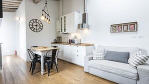 A modern kitchen with white cabinets, a dining table with chairs, a white sofa, and a wall clock. - <h3>Central Nest</h3>Located in Via Guelfa, in the heart of the historic center of Florence, this delightful apartment offers a comfortable and modern refuge just steps away from the Central Market and the Santa Maria Novella Station.On the third and top (Firenze)