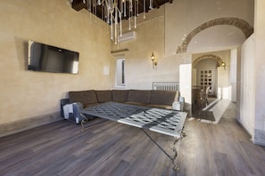 Een moderne woonkamer met een modulaire bank, een grote flatscreen-televisie aan de muur en een bijzondere geometrische salontafel.