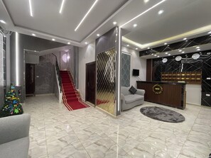 A modern lobby with a marble floor, a red carpeted staircase, a reception desk, and a Christmas tree. - Rehana Pyramids View (Giza)