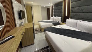 Ett modernt hotellrum med två sängar, ett skrivbord och en TV.