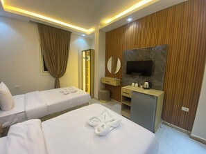 Une chambre d’hôtel avec deux lits, une télévision, un minibar et un mur recouvert de panneaux en bois.