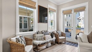 A sunroom with wicker furniture, large windows, and a view of the outside.
